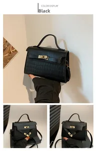 Detail view of black crocodile pattern handbag with golden turn-lock closure and leather strap