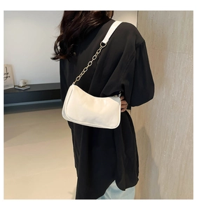 Detail of white baguette shoulder bag featuring gold chain and sleek faux leather finish