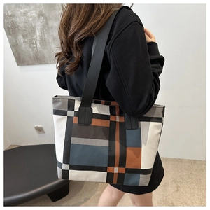 Detail of a geometric patchwork tote bag with wide strap worn by a model