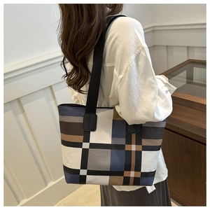 Large tote bag featuring geometric color-block design in navy and brown worn by model