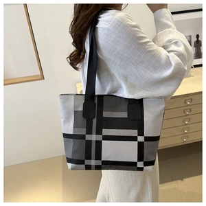 Close-up of a large black and white plaid tote bag featuring woven fabric and wide straps