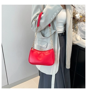 Detail of red faux leather shoulder bag with gold chain strap and zipper closure