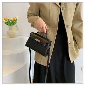 Close-up of black crocodile pattern handbag on a model in a minimalist setting