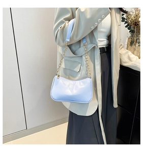 Detail of light blue leather shoulder bag with gold chain strap on model