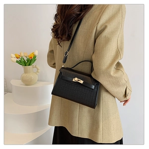 Close-up of black crocodile-embossed leather texture and metallic turn-lock closure detail
