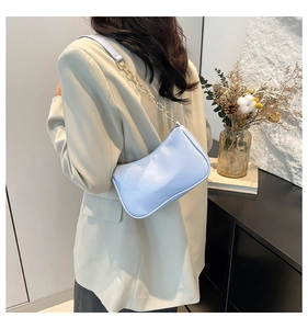 Light blue faux leather underarm bag with gold chain strap shown in a modern interior