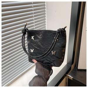 Détail du sac seau noir froissé avec boucles papillon argentées et bandoulière corde