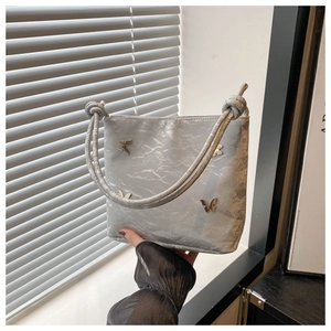 Gros plan du sac seau plissé gris argent avec papillon métallique et bandoulière nouée