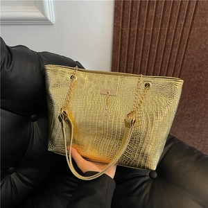 Detailed view of gold tote bag with embossed crocodile pattern and golden deer pendant