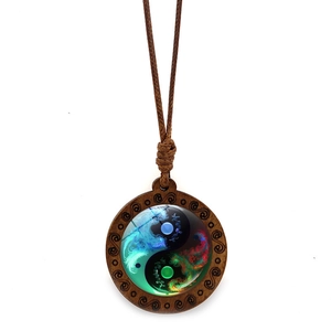 Detail of vintage wooden Tai Chi pendant with colorful glass inlay and braided rope