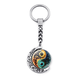 Close-up of a rotating Yin Yang moon keychain with a blue and orange nebula glass pendant