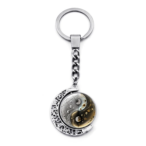 Detail of a rotating Yin Yang glass pendant keychain with crescent moon frame