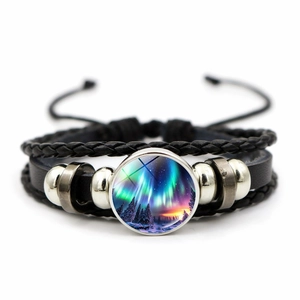 Detail van de lederen armband met sterrenstelsel hanger en gevlochten zwarte koorden