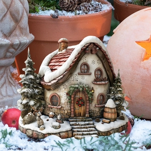 Macro shot of snow-covered Christmas cottage garden stake with reindeer and wreath