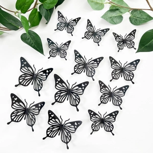 Set van 11 zwarte holle 3D vlinder muurstickers in diverse maten op een witte achtergrond