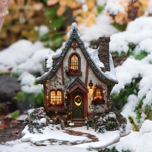 Macro detail of a miniature Christmas house with snow-covered roof and warm LED windows