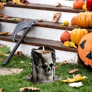 Halloween skull candle garden stake decoration with glowing flame on backyard lawn