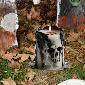 Close-up of a skull candle holder with black fluid art textures and a warm glowing tealight