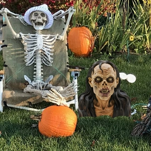 Realistic zombie head with long hair for Halloween garden decoration on sunny lawn