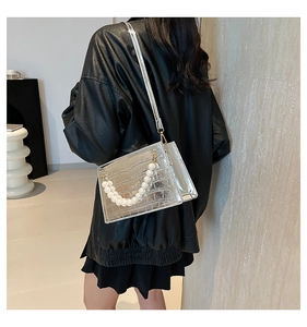 Detail of silver crocodile pattern evening bag with decorative pearl handle and chain strap
