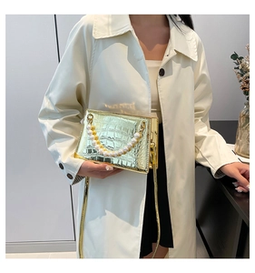 Close-up of gold crocodile-pattern clutch with pearl bead handle and metallic finish