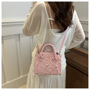 Detail of pink denim crossbody bag with frayed fringe texture shown on a model