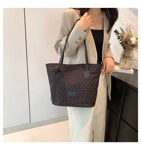 Dettaglio borsa shopper nera con cuori rossi, fiocco in pizzo e manici lunghi