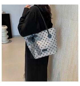 Dettaglio di una borsa shopper grigia a pois con un fiocco in pizzo nero sulla spalla