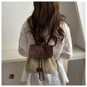 Detail of straw woven drawstring backpack with brown leather trim on female model