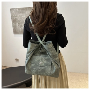 Vue détaillée du sac fourre-tout vintage vert avec papillon en métal et texture lavée au dos