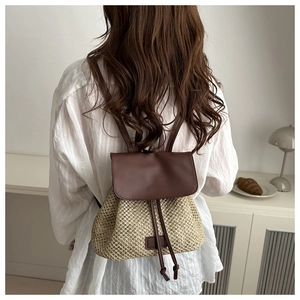 Detail of retro straw backpack with brown leather straps and natural woven texture
