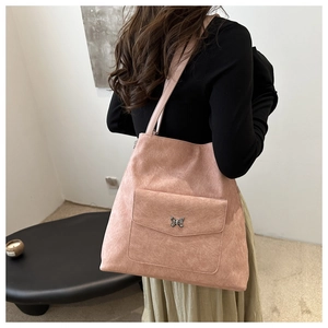 Détail du sac cabas rose en faux daim avec poche à rabat frontale et boucle papillon argentée