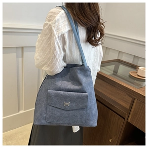 Sac fourre-tout en denim bleu avec une poche à rabat et boucle en métal papillon
