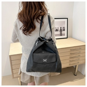 Détail du sac cabas noir avec boucle papillon argentée et fermetures éclair latérales