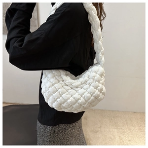 Détail latéral du sac hobo blanc matelassé porté à l'épaule avec une texture nuageuse