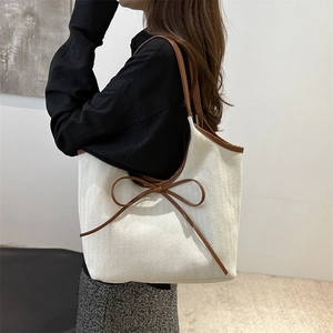 Minimalist beige herringbone tote bag with brown leather bow and shoulder straps
