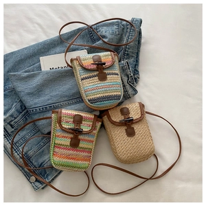 Close-up of woven straw mini bags with colorful stripe patterns and brown leather strap