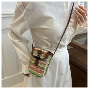 Detail of colorful rainbow woven straw crossbody bag with brown leather flap and strap