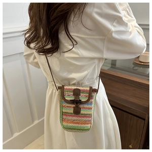 Detail of multi-color woven crossbody phone bag with leather trim and horn buckle closure