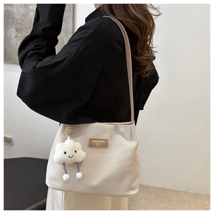 Detail of off-white waffle texture tote bag with plush cloud charm and brown logo