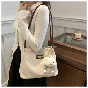 Detail of cream knit tote bag with brown leather straps and cloud charm accessory