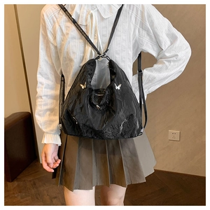 Detail of black pleated texture backpack with silver butterfly metal charms for women