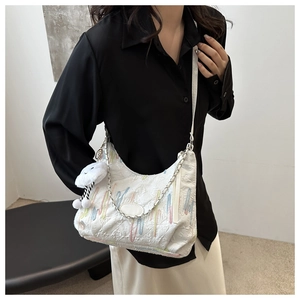 Detail of white tote bag featuring colorful embroidery and cloud plush charm decoration