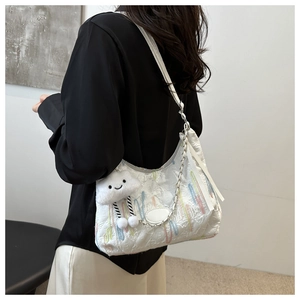 Détail du sac cabas blanc avec broderies colorées et breloque en forme de nuage