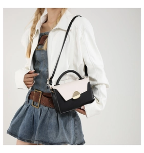 Detail of a chic black and white leather handbag with elegant gold metal clasp on model