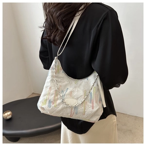 Detail of white textured canvas shoulder bag with colored embroidery and metal chain strap