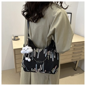 Détail du sac noir avec broderie ondulée colorée et pendentif nuage en peluche blanc