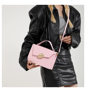 Pink minimalist leather crossbody bag with golden hardware shown with black leather outfit