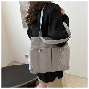 Detail view of large grey canvas tote bag with front pockets and silver snap buttons
