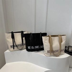 Trois sacs cabas en toile minimalistes en crème et noir avec des détails de lettres
